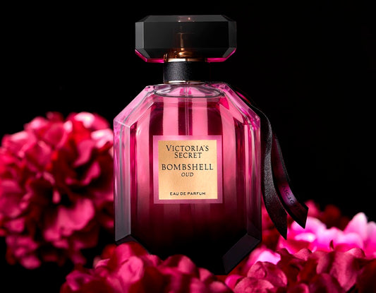 Victoria's Secret Bombshell Oud perfume bottle with pink flowers on a black background