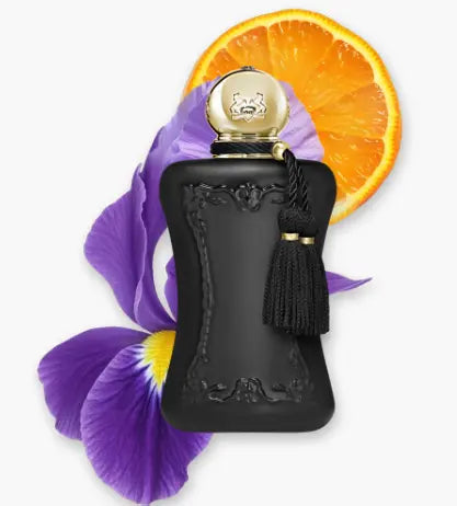 Black perfume bottle with gold cap and tassel, placed on a white background with an orange slice and purple flower.