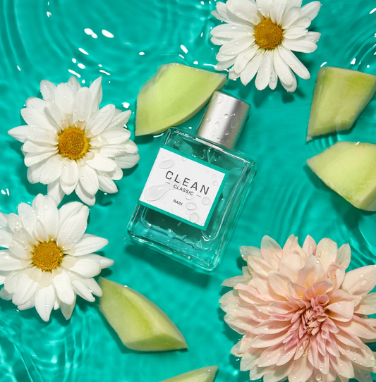 Clean perfume bottle with flowers and watermelon pieces on a teal background
