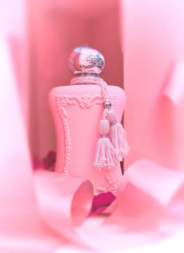 Pink perfume bottle with decorative elements on a pink background
