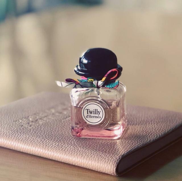 Perfume bottle labeled 'Twilly d'Hermes' on a textured surface with a blurred background
