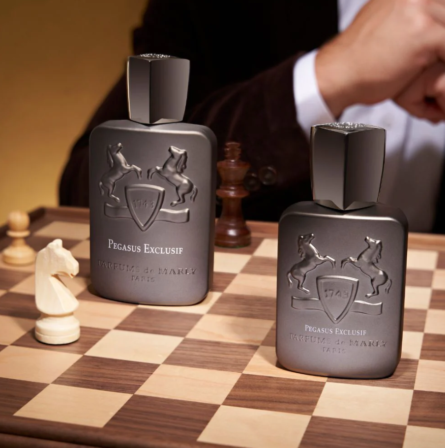 Two Pegasus Exclusif perfume bottles on a chessboard with chess pieces.