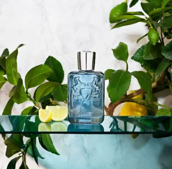 Blue bottle with silver cap on a glass surface with green leaves and lemons in the background