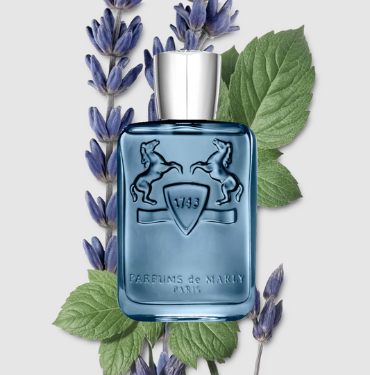 Blue perfume bottle with silver cap on a white background with lavender and green leaves