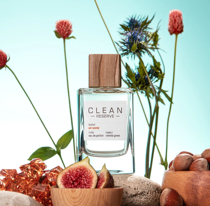 Clean Reserve perfume bottle with flowers and figs on a light blue background