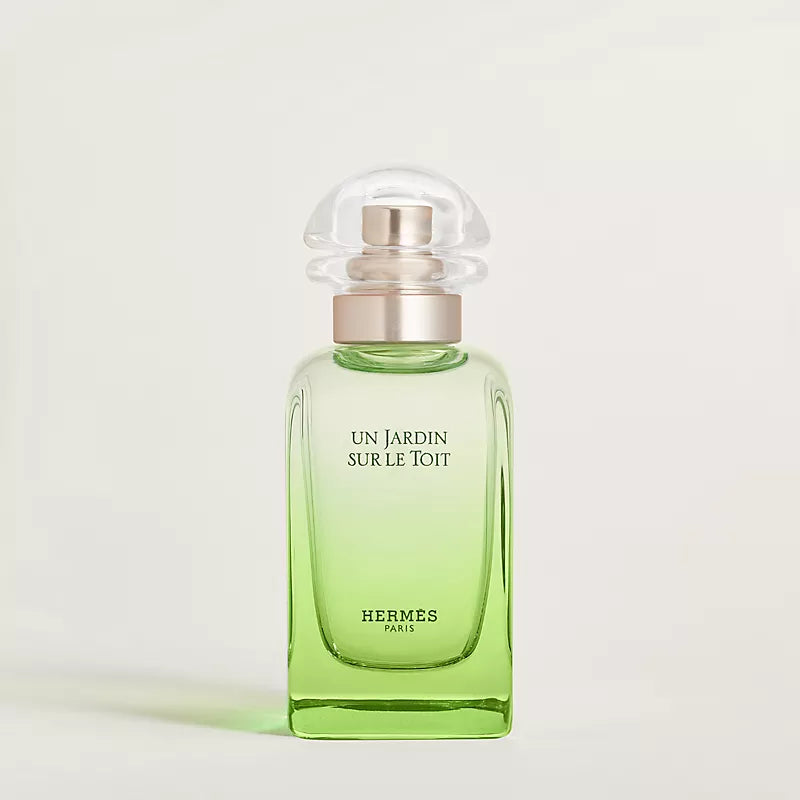 Green perfume bottle with silver cap on a light gray background