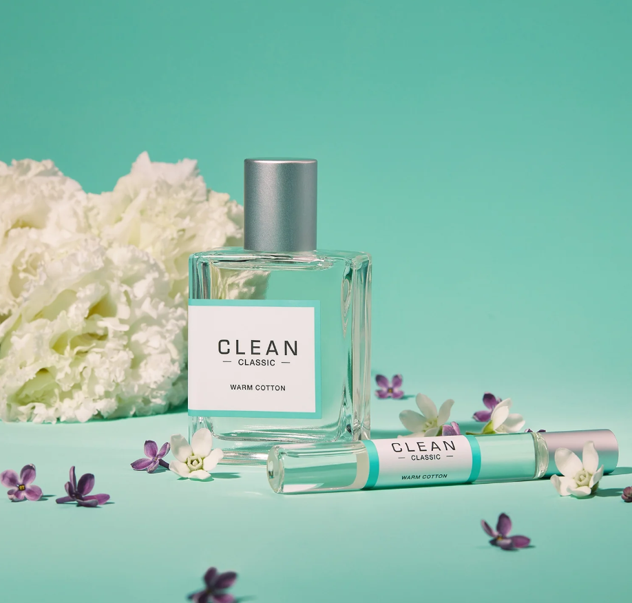 Clean perfume bottle and rollerball with flowers on a teal background