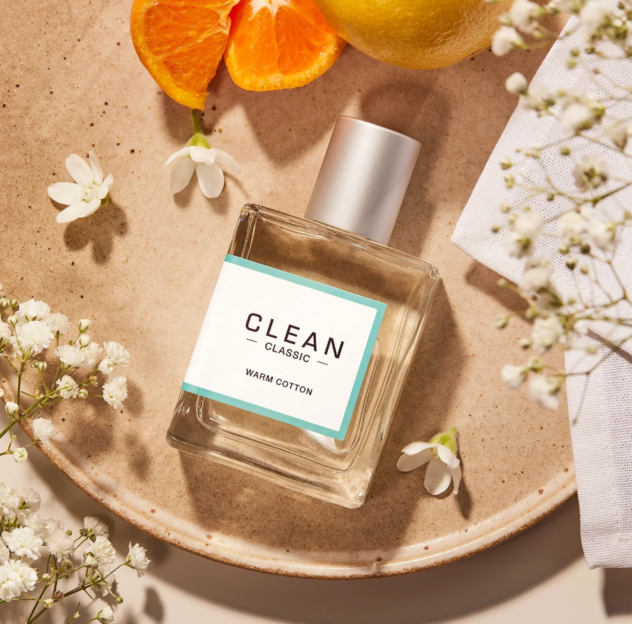 Clean perfume bottle on a ceramic plate with oranges and flowers