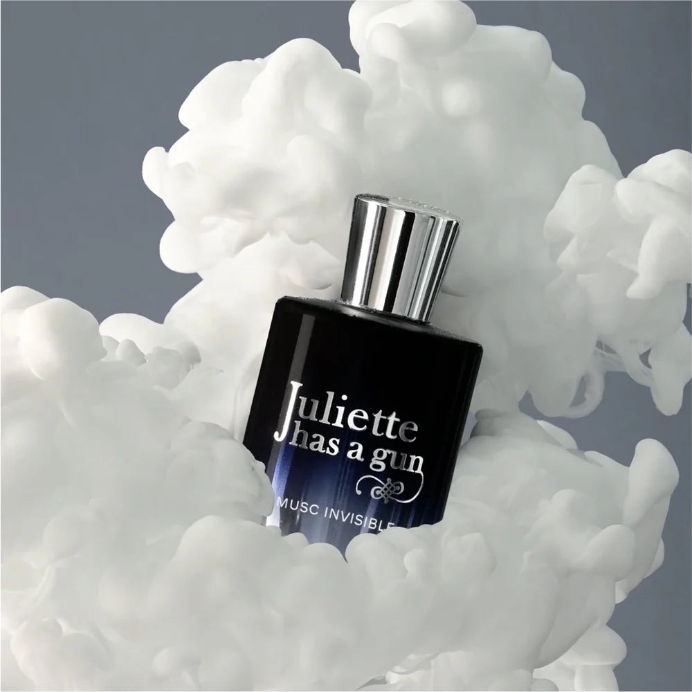 Perfume bottle with 'Juliette has a gun' branding surrounded by white smoke on a gray background