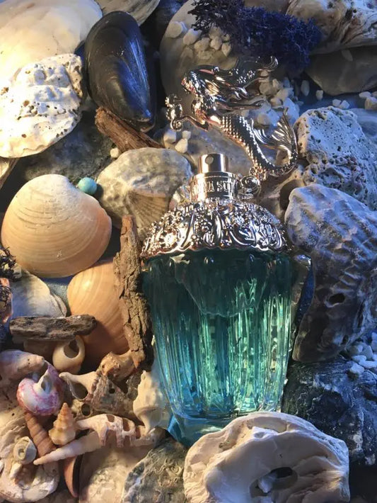 Blue perfume bottle surrounded by seashells and marine decorations