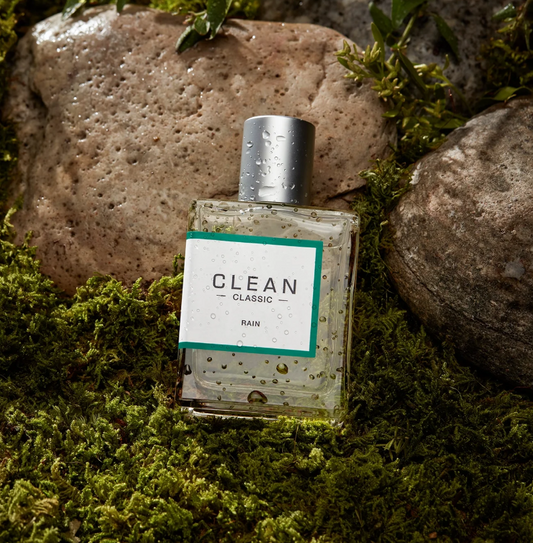 Clean perfume bottle on a mossy surface with rocks in the background