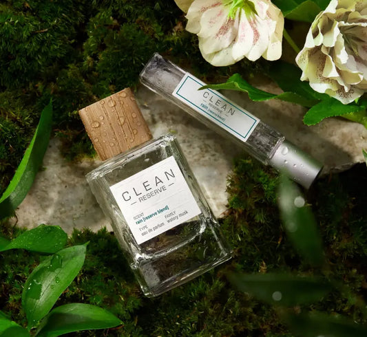 Two 'Clean' perfume bottles on a natural background with flowers and leaves.