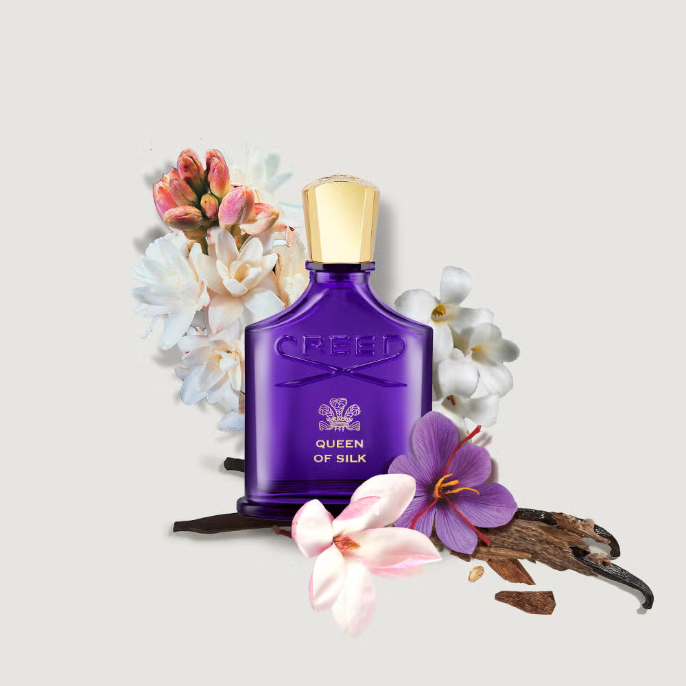 Purple Creed perfume bottle with flowers and vanilla beans on a light gray background