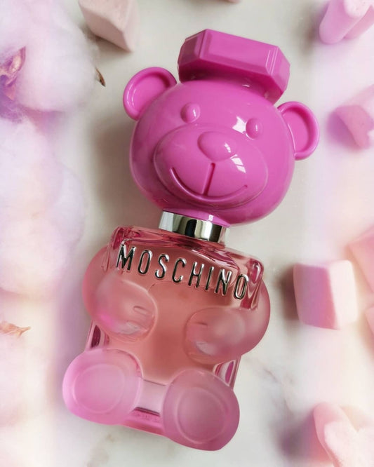 Pink teddy bear-shaped Moschino perfume bottle on a soft pink background