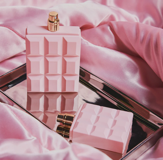 Pink perfume bottle with geometric design on a pink fabric background
