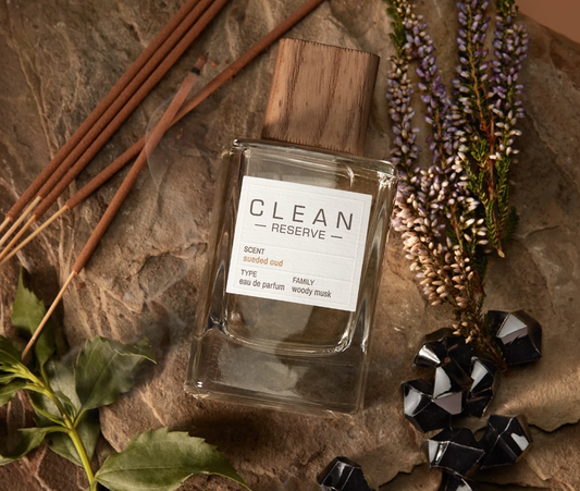 Clean Reserve diffuser bottle with reeds, flowers, and decorative stones on a stone surface