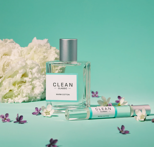 Clean perfume bottle and rollerball with flowers on a teal background